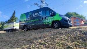Grüner Baiant-Transporter mit Anhänger auf einer Wiese